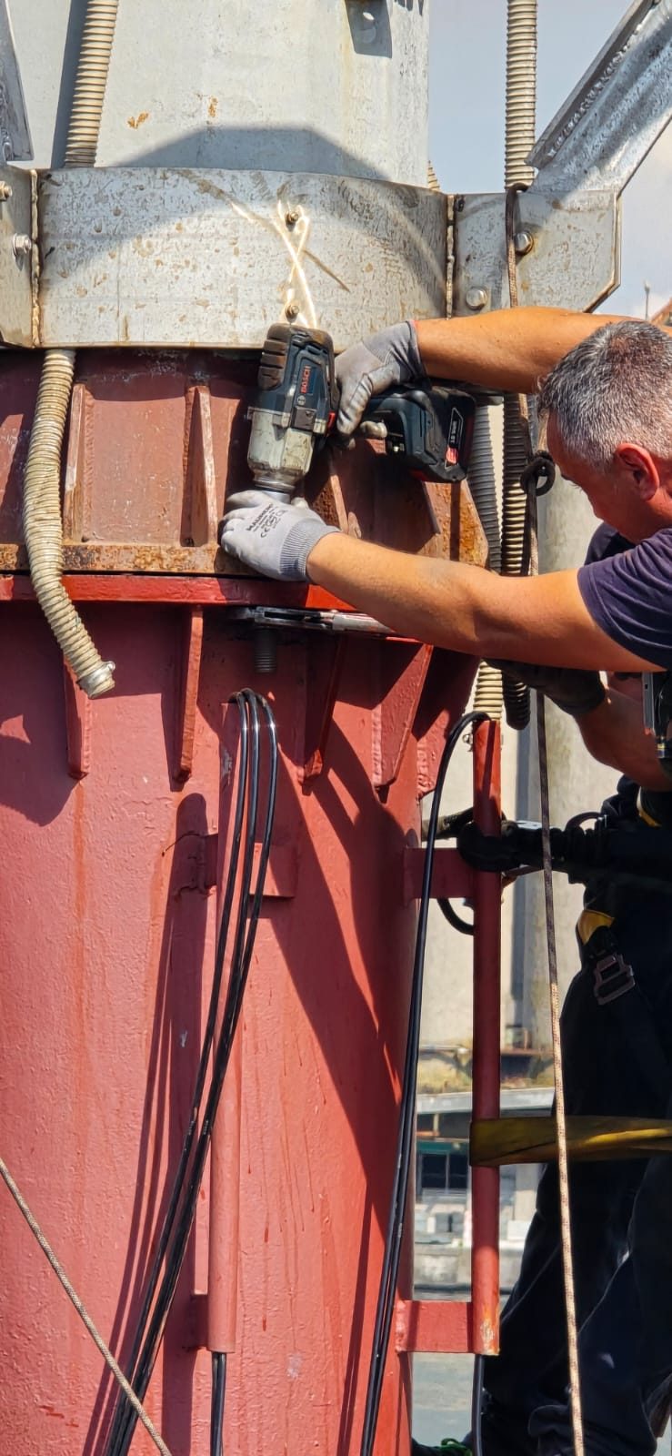 Tecnico al lavoro con avvitatore sulla sommità della struttura galleggiante